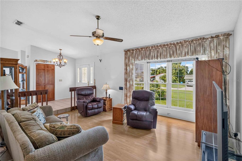 A living room with light wood flooring, two leather recliners, a sofa, and a bay window — 4803 LYNN OAKS CIRCLE, DOVER, FL
