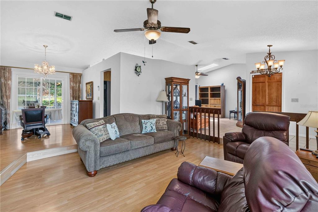 A living room with light wood floors, a brown sofa, leather recliners, and a ceiling fan — 4803 LYNN OAKS CIRCLE, DOVER, FL