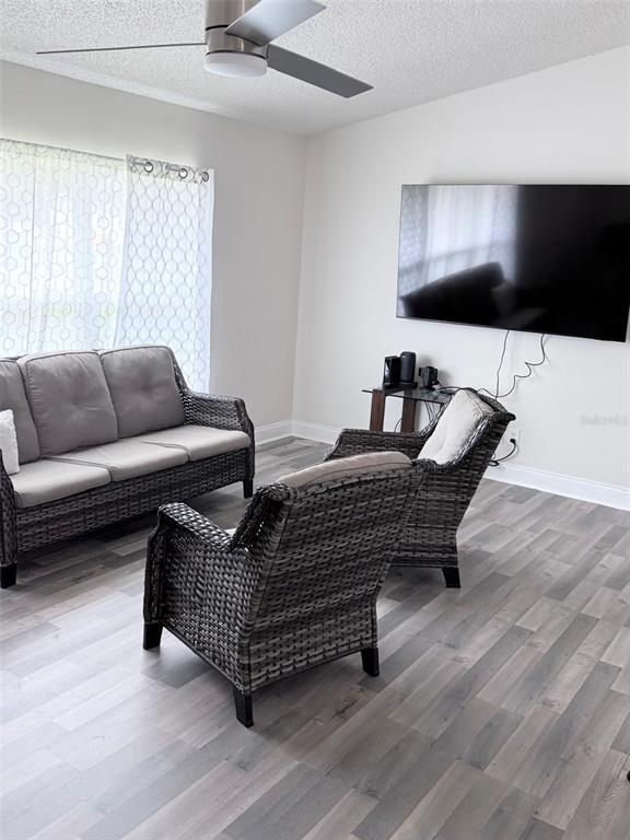A living room features gray wicker furniture, light wood-look flooring, and a wall-mounted television — 3237 LONDON AVENUE, DELTONA, FL