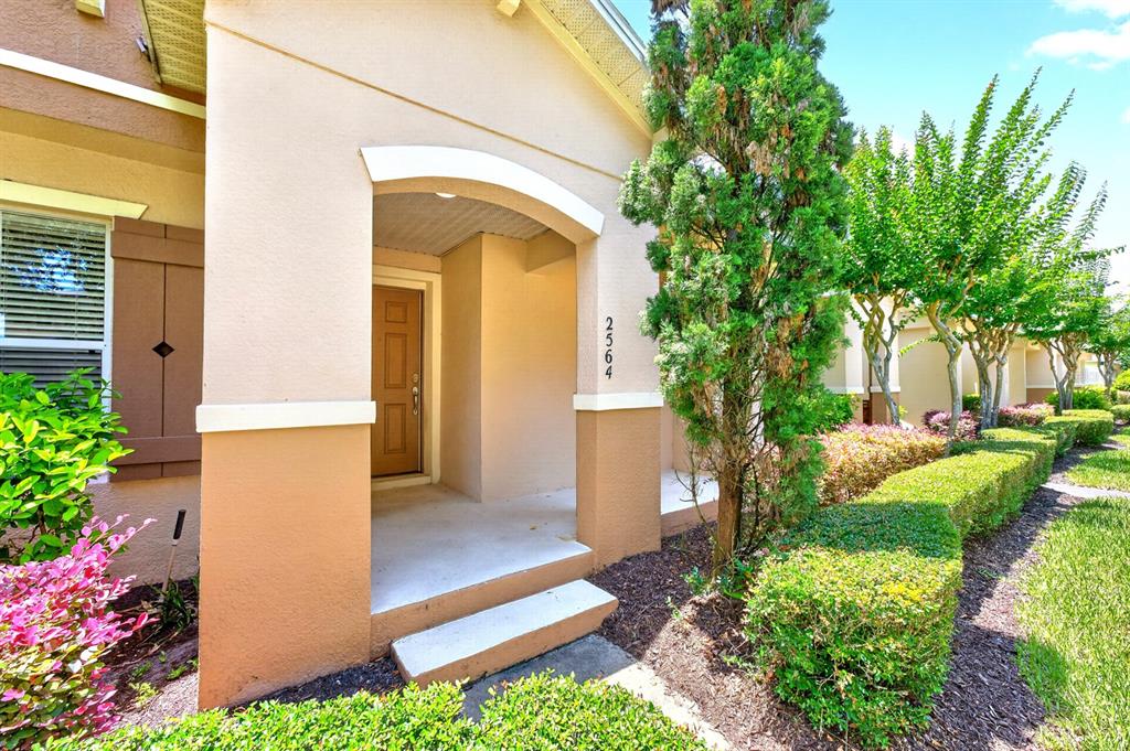 The exterior of a tan stucco house features a covered entryway and manicured landscaping — 2564 ABEY BLANCO DRIVE, ORLANDO, FL