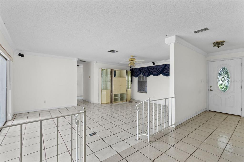 A tiled living area features a white metal railing, a ceiling fan, and a glass-paneled door — 2467 FIELDINGWOOD ROAD, MAITLAND, FL