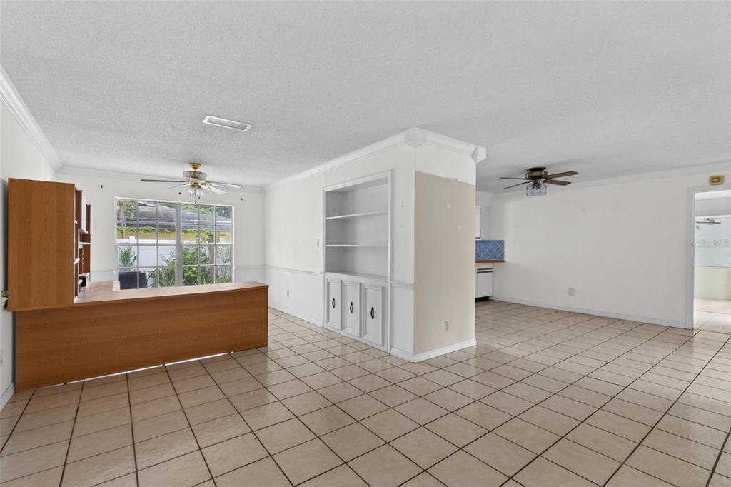 A room with beige tile flooring, a built-in white shelving unit, and a wooden desk — 2467 FIELDINGWOOD ROAD, MAITLAND, FL