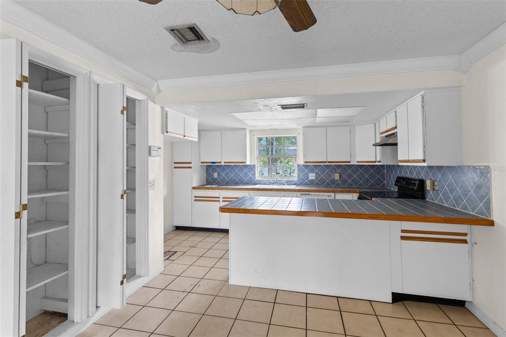 A kitchen with white cabinets, blue tile countertops, and a tiled floor — 2467 FIELDINGWOOD ROAD, MAITLAND, FL