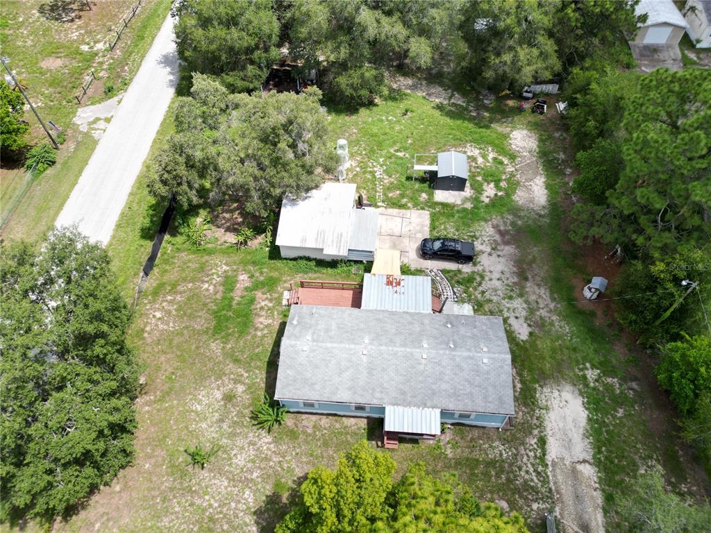 An aerial view shows a house with a metal roof, a deck, and several outbuildings — 17828 ALEXSON STREET, SPRING HILL, FL