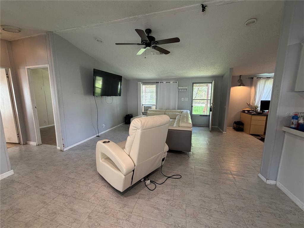A living room features light tile flooring, a white leather sectional, and a matching recliner — 17828 ALEXSON STREET, SPRING HILL, FL