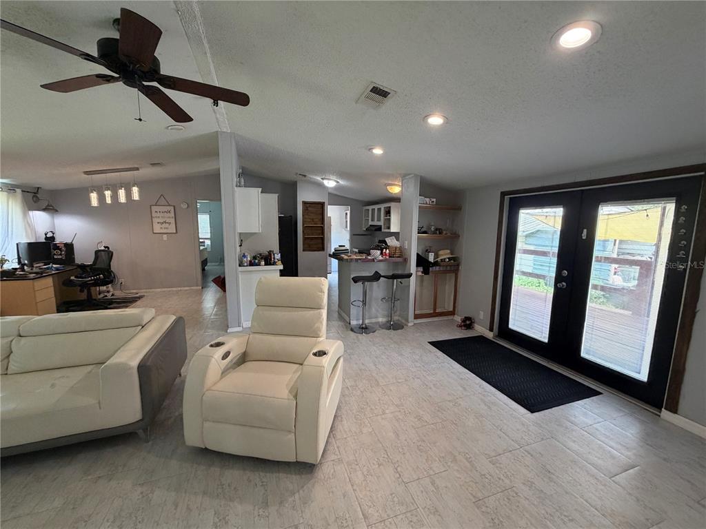 A living room features light tile flooring, a white recliner, and double glass doors — 17828 ALEXSON STREET, SPRING HILL, FL