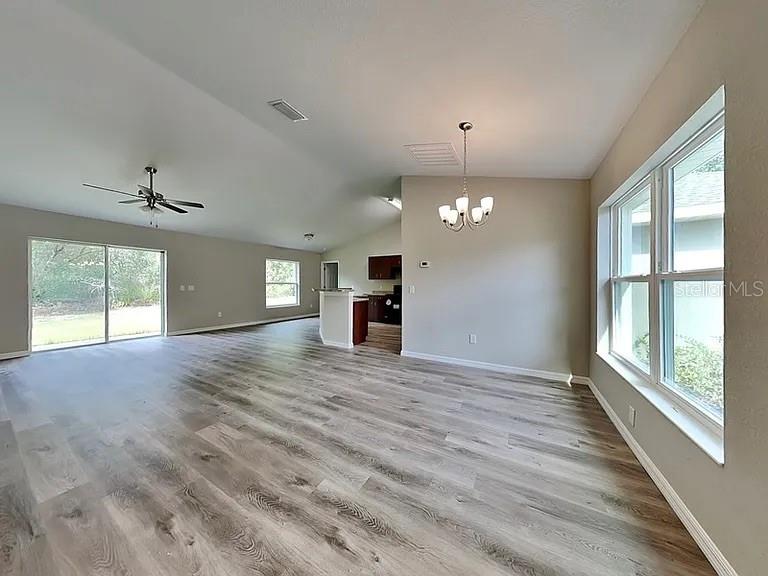 An open-concept living and dining area features light wood-look flooring and a vaulted ceiling — 3584 W BURGANDY DRIVE, CITRUS SPRINGS, FL