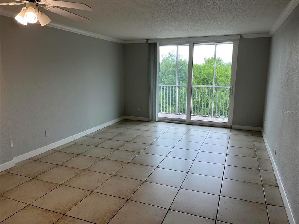 An empty room features light-colored tile flooring, gray walls, a ceiling fan, and sliding glass doors — 2610 COCONUT BAY LN LANE UNIT 733, SARASOTA, FL