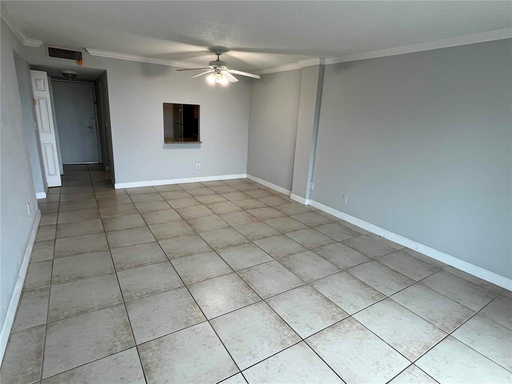 An empty room features light gray walls, large square floor tiles, and a ceiling fan — 2610 COCONUT BAY LN LANE UNIT 733, SARASOTA, FL