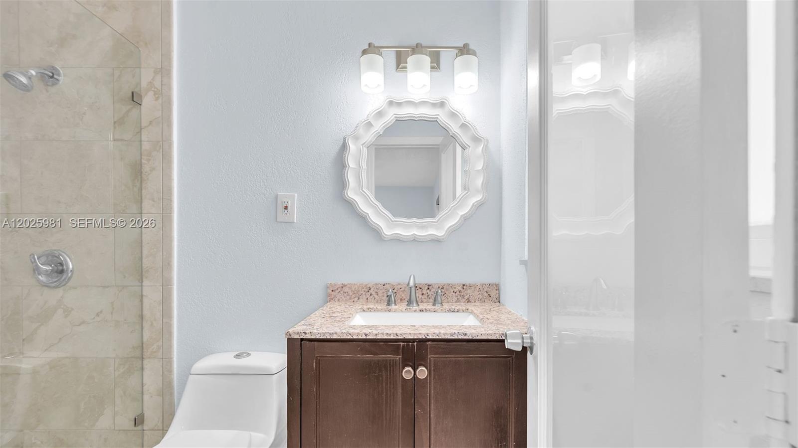 A bathroom features a dark wood vanity, granite countertop, white mirror, and a glass-enclosed shower — MIAMI, FL