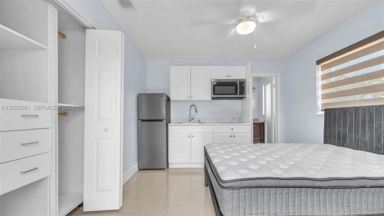 A studio apartment features a kitchenette, a closet, and a bed with a grey headboard — MIAMI, FL