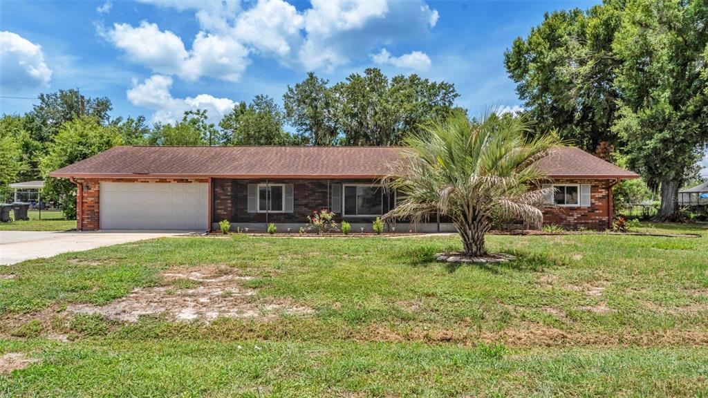 A single-story brick house with a two-car garage and a palm tree in the yard — 3180 FLAMINGO LANE, MULBERRY, FL