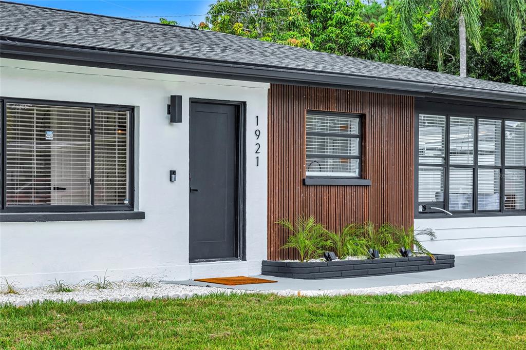 The exterior of a house features white walls, vertical wood slats, and a dark door — 1921 FERN AVENUE, SARASOTA, FL