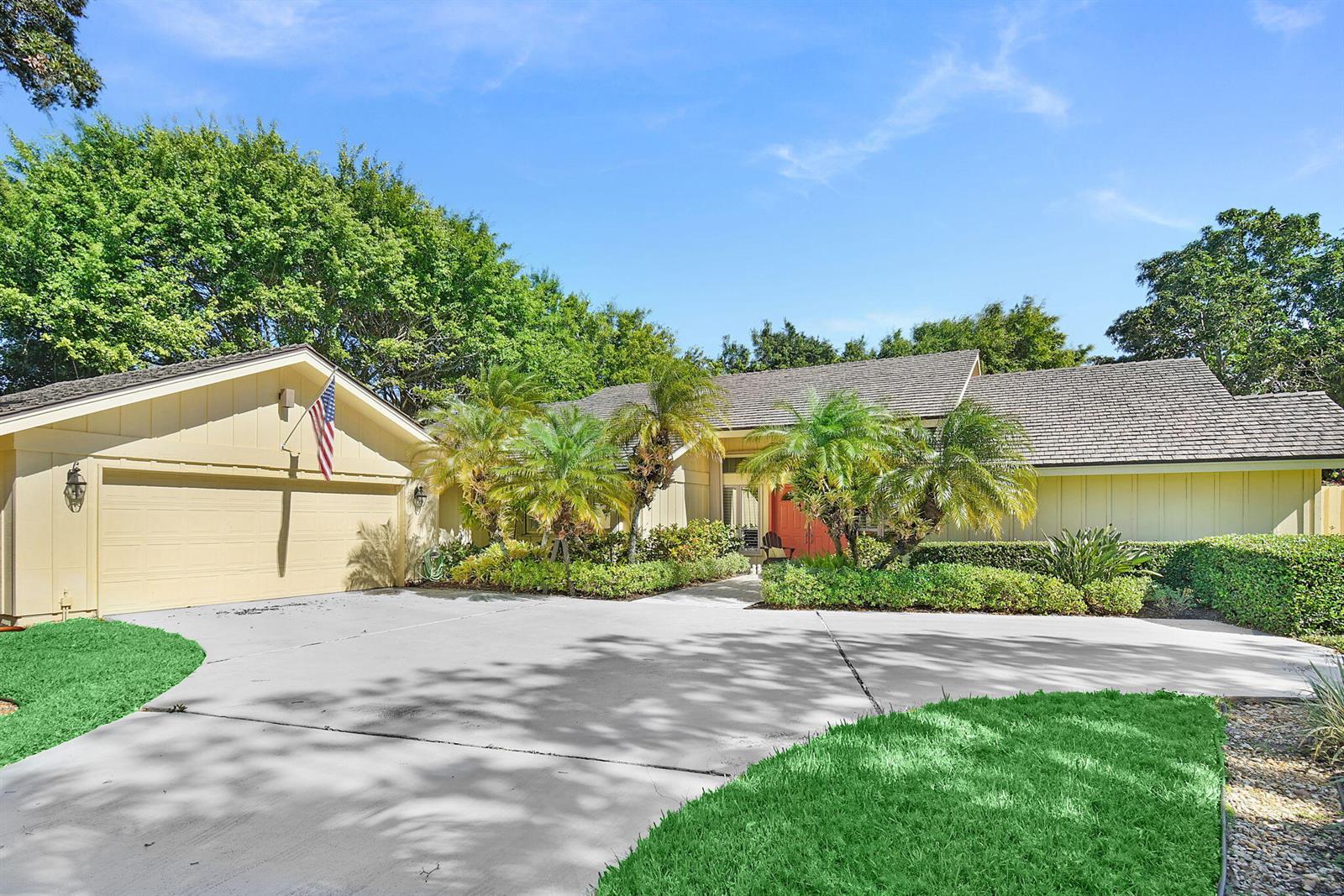 A single-story house with a beige exterior, a two-car garage, and a palm-lined front yard — 6111 SE Winged Foot Drive, Stuart FL 34997, STUART, FL