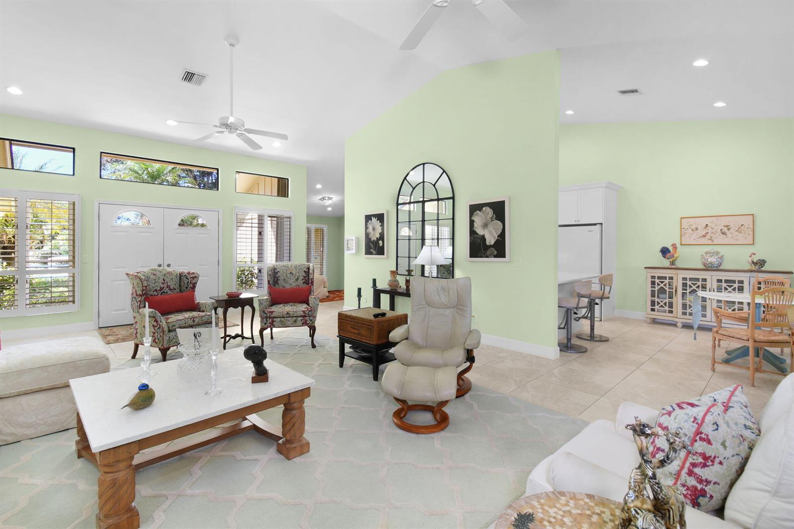 A living room with light green walls, tile flooring, a marble coffee table, and vaulted ceilings — 6111 SE Winged Foot Drive, Stuart FL 34997, STUART, FL