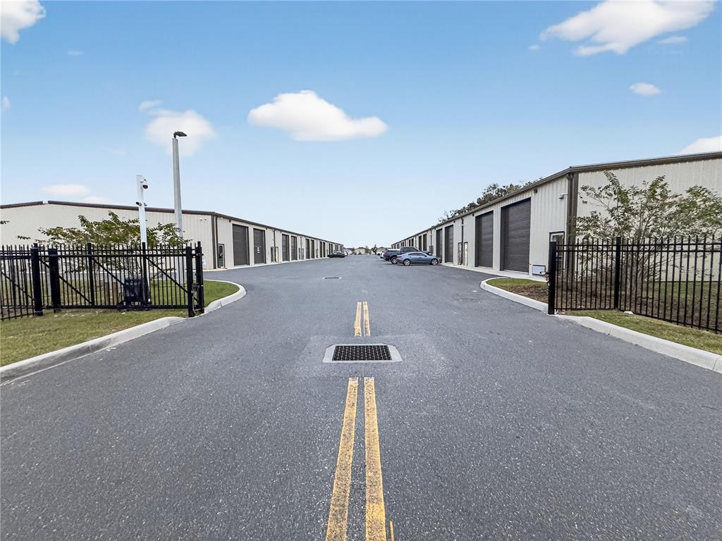 An asphalt driveway leads between two rows of metal storage buildings with roll-up doors — 4707 COUNTY ROAD 156, WILDWOOD, FL
