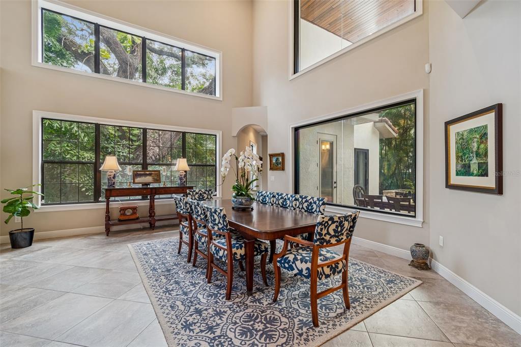 A dining room with a high ceiling, large windows, tile floors, and a patterned rug — 2906 W HAWTHORNE ROAD, TAMPA, FL