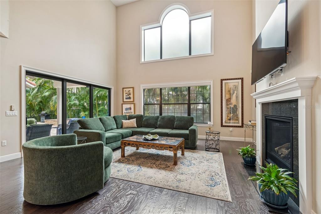 A living room features a green sectional sofa, a fireplace, and large windows — 2906 W HAWTHORNE ROAD, TAMPA, FL