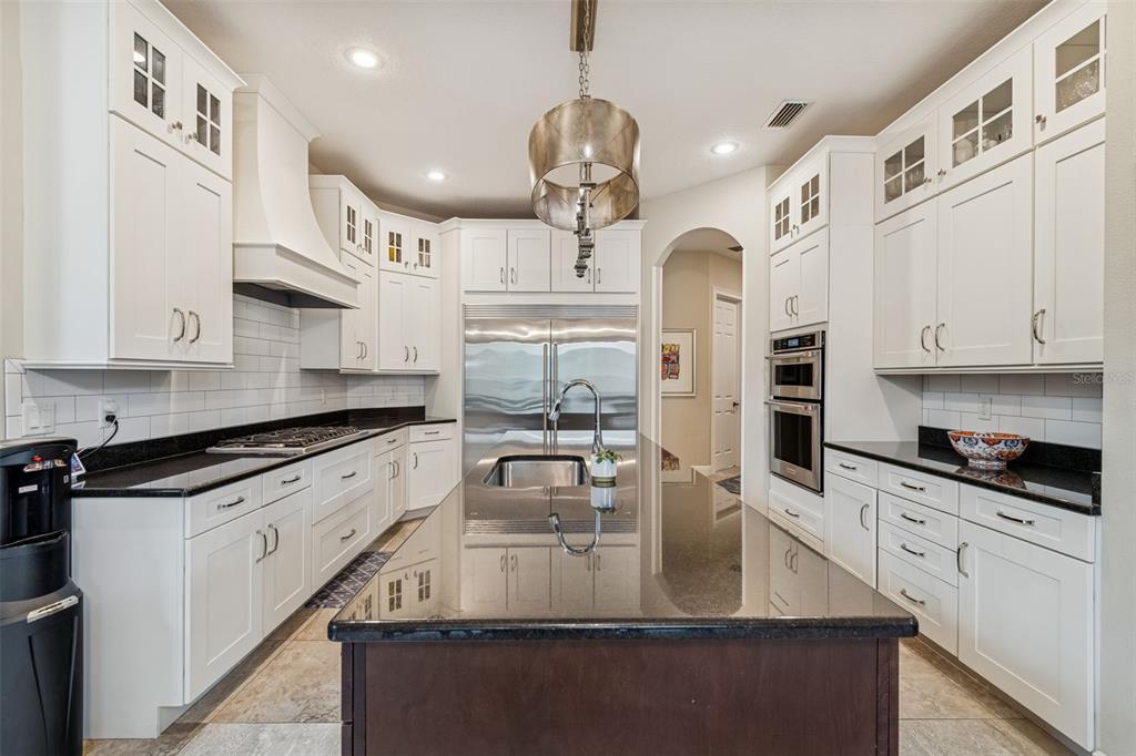 A kitchen features white cabinetry, black countertops, a large center island, and stainless steel appliances — 2906 W HAWTHORNE ROAD, TAMPA, FL