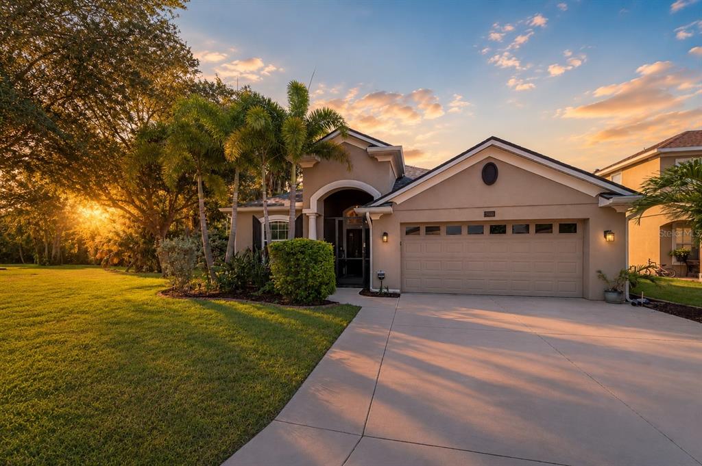 A single-story house with a beige stucco exterior, a two-car garage, and palm trees — 5030 58TH TERRACE E, BRADENTON, FL