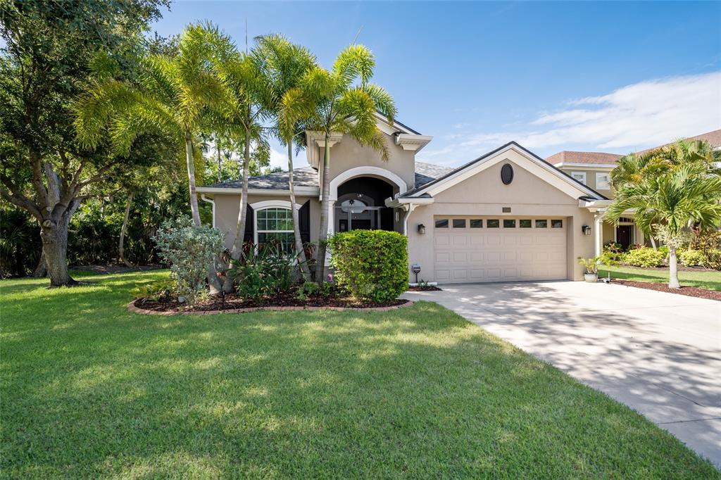 A single-story house with a beige stucco exterior, a two-car garage, and palm trees — 5030 58TH TERRACE E, BRADENTON, FL
