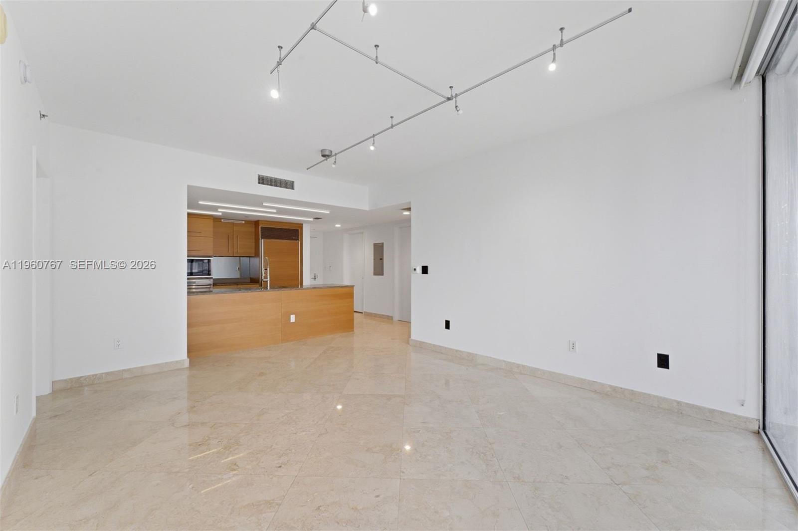 An open-concept living area features light-colored tile flooring, white walls, and a wood-paneled kitchen — 475 Brickell Ave # 3513, Miami FL 33131, MIAMI, FL