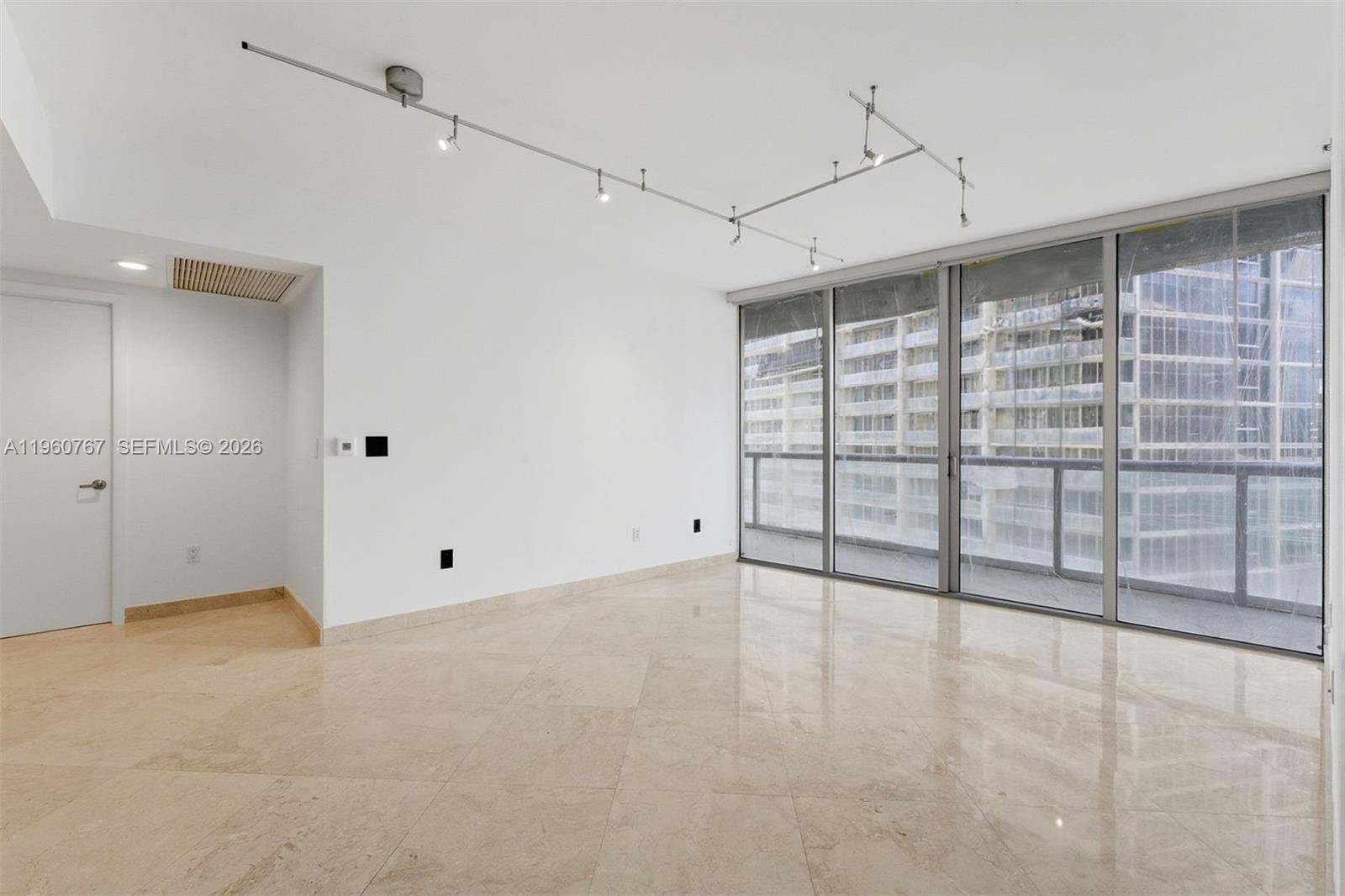 An empty room features beige tile floors, white walls, track lighting, and floor-to-ceiling windows — 475 Brickell Ave # 3513, Miami FL 33131, MIAMI, FL