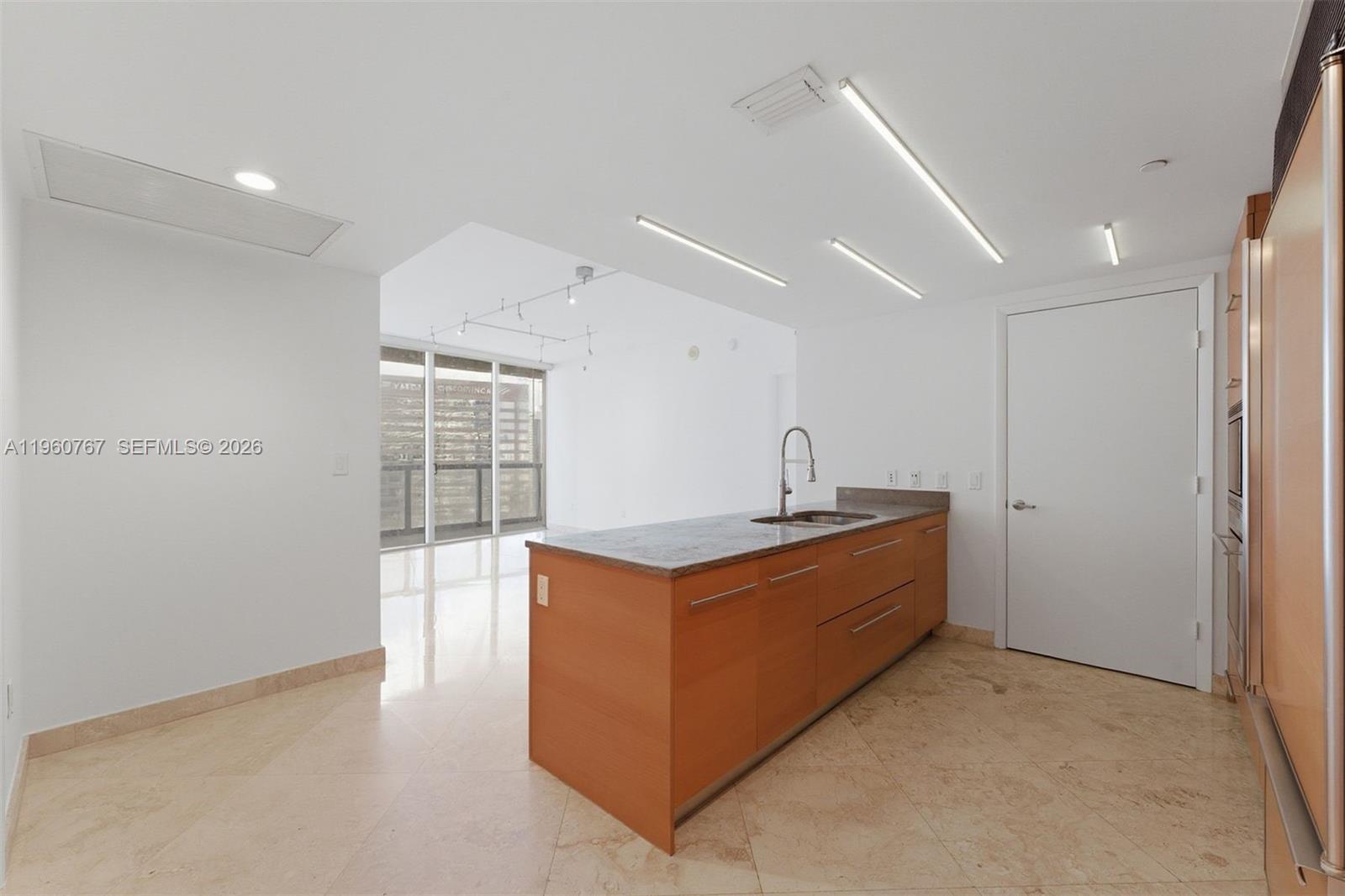 A modern kitchen features a wooden island with a stone countertop and light tile flooring — 475 Brickell Ave # 3513, Miami FL 33131, MIAMI, FL