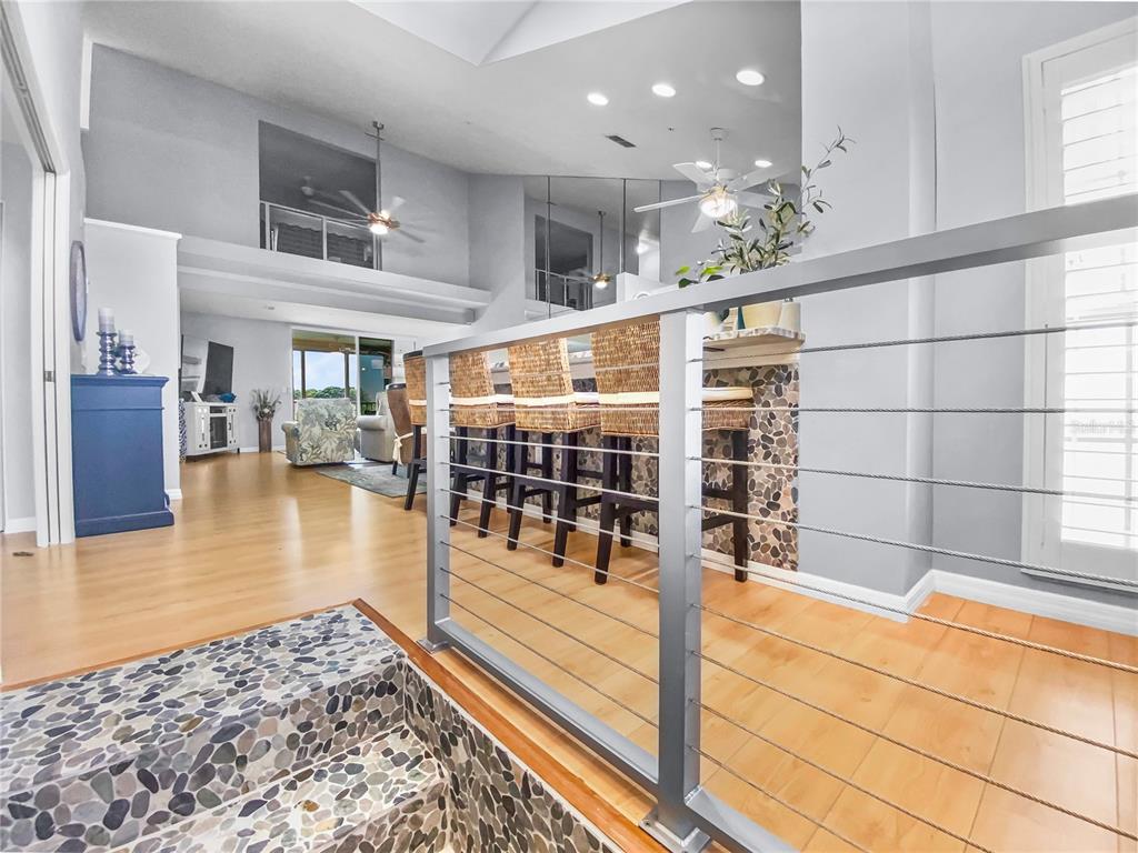 A multi-level interior features a stone-tiled staircase, a cable railing, and a kitchen breakfast bar — 8370 WINGATE DRIVE UNIT 725, SARASOTA, FL