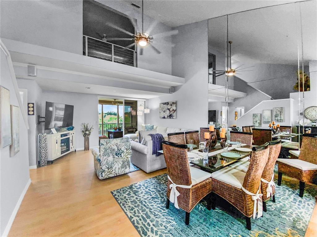A dining area with wicker chairs and a living room with a vaulted ceiling — 8370 WINGATE DRIVE UNIT 725, SARASOTA, FL