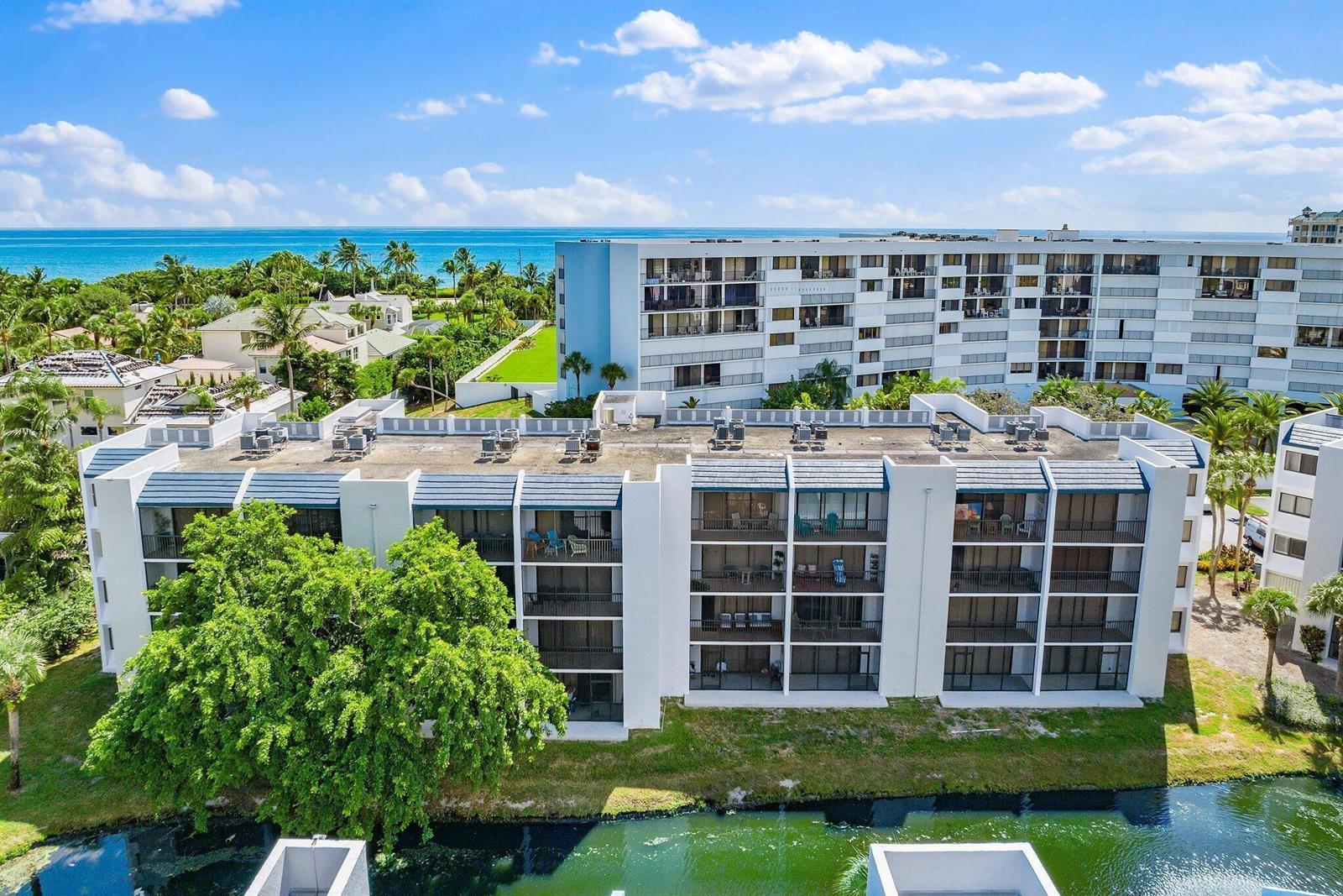 An aerial view shows a multi-story white apartment building next to a canal and ocean — 1605 S Us Hwy 1 # A106, Jupiter FL 33477, JUPITER, FL