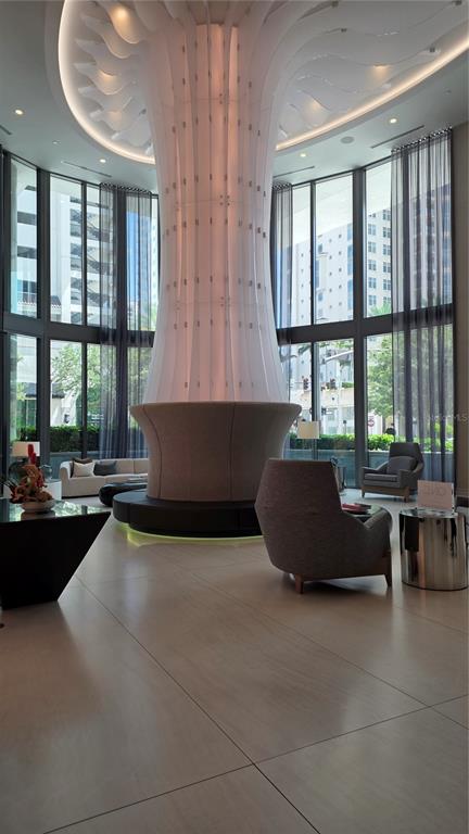A modern lobby features a large, illuminated central pillar, floor-to-ceiling windows, and contemporary lounge seating — 100 1ST AVENUE N UNIT 2406, ST PETERSBURG, FL