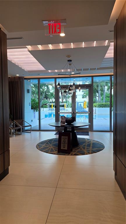 A modern lobby features a round table, pendant lighting, and a view of an outdoor pool — 100 1ST AVENUE N UNIT 2406, ST PETERSBURG, FL