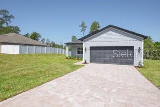 A single-story house with a gray exterior, a dark garage door, and a paved driveway — 604 MARION OAKS LANE, OCALA, FL
