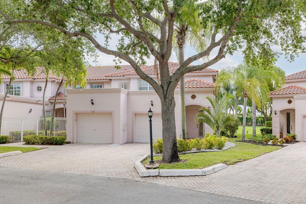 A two-story pink stucco townhouse with a tile roof, two garage doors, and a paved driveway — 8050 Aberdeen Drive # 202, Boynton Beach FL 33472, BOYNTON BEACH, FL