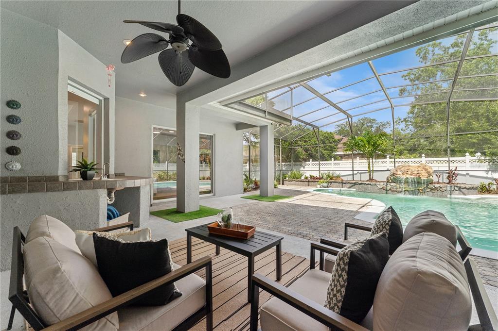 A covered patio features outdoor seating, a small kitchen counter, and a screened-in swimming pool — 4431 LITTLE WATER STREET, ORLANDO, FL