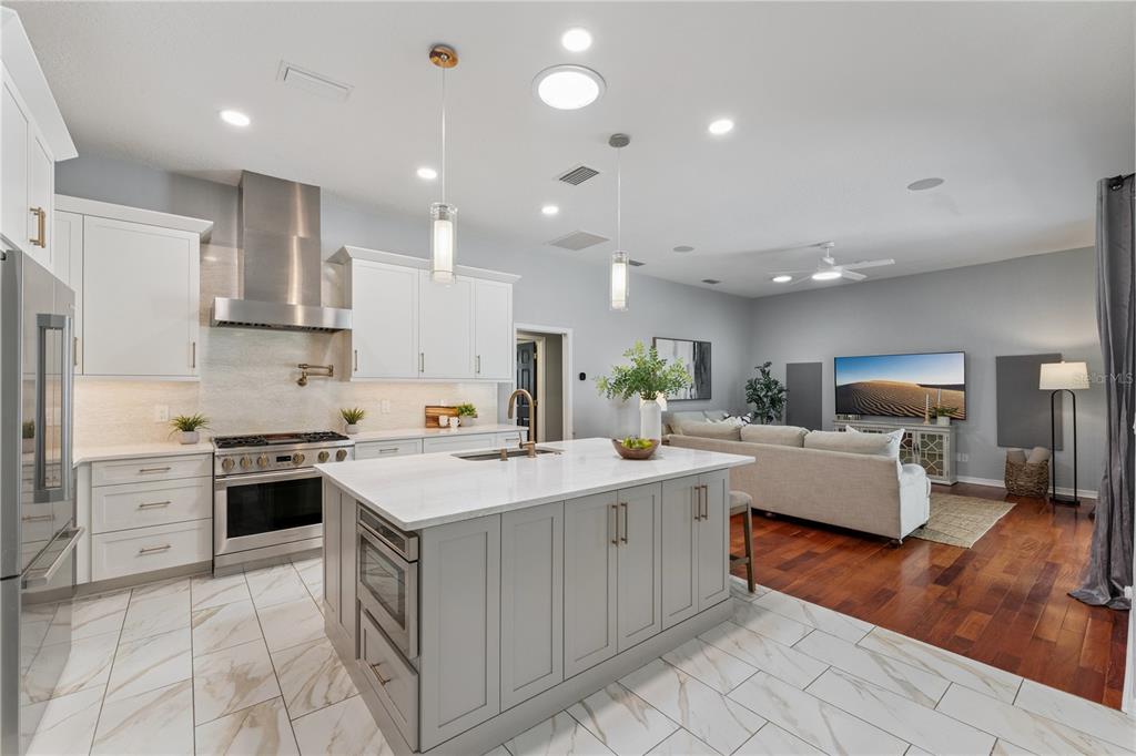 A modern open-concept kitchen with white cabinets, a gray island, and stainless steel appliances — 4431 LITTLE WATER STREET, ORLANDO, FL