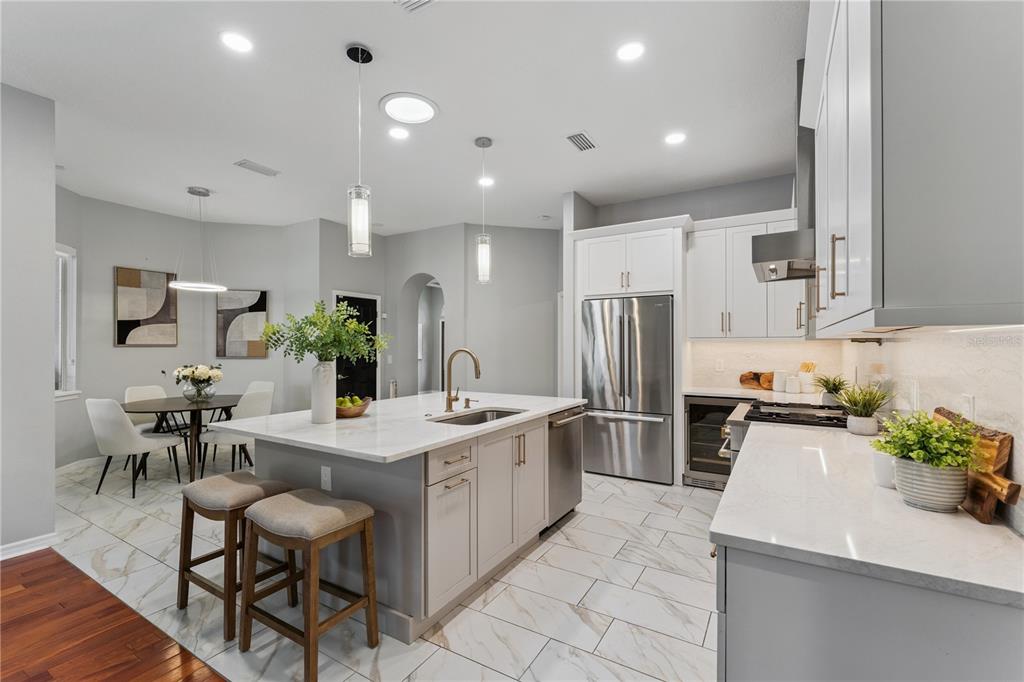 A modern kitchen features a marble-topped island, white cabinetry, stainless steel appliances, and tile flooring — 4431 LITTLE WATER STREET, ORLANDO, FL