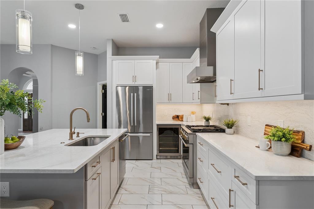 A modern kitchen features white cabinetry, stainless steel appliances, a marble island, and tile flooring — 4431 LITTLE WATER STREET, ORLANDO, FL