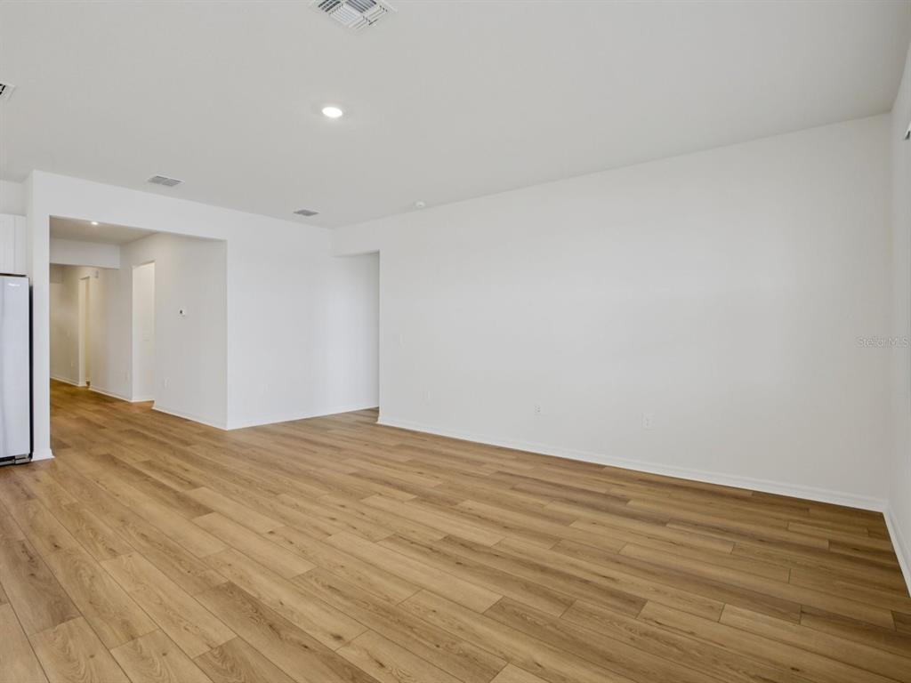 An empty room with white walls, recessed lighting, and light wood-look flooring — 9013 VENETIA COURT, PALMETTO, FL