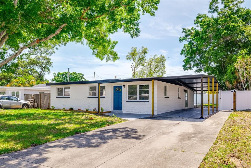A white single-story house with a blue front door and an attached carport — 9596 GROVELAND STREET, SEMINOLE, FL