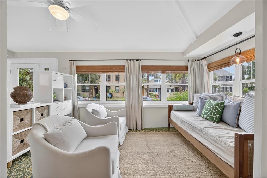 A sunroom features a daybed, two white armchairs, a jute rug, and large windows — 221 13TH AVENUE NE, ST PETERSBURG, FL