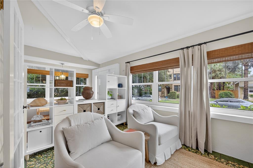A sunroom features two armchairs, white shelving units, and large windows with curtains — 221 13TH AVENUE NE, ST PETERSBURG, FL