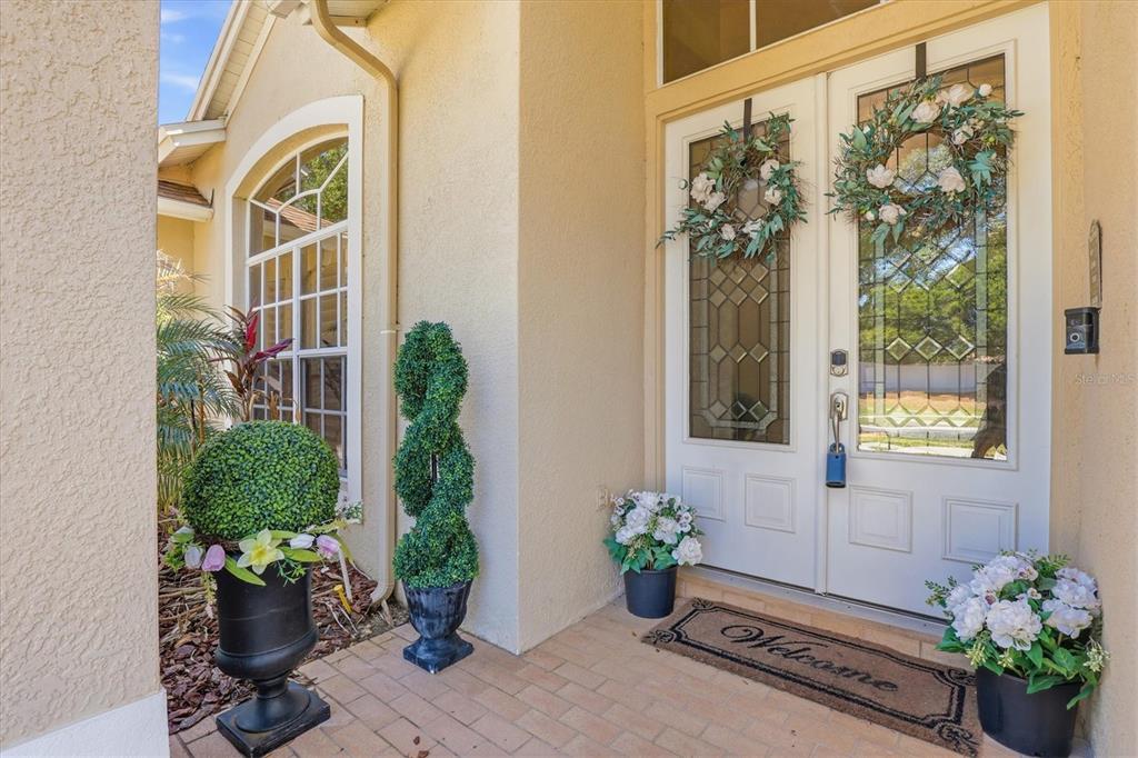 A front entryway features double doors with glass inserts, decorative wreaths, and potted plants — 8331 GOLDEN PRAIRIE DRIVE, TAMPA, FL