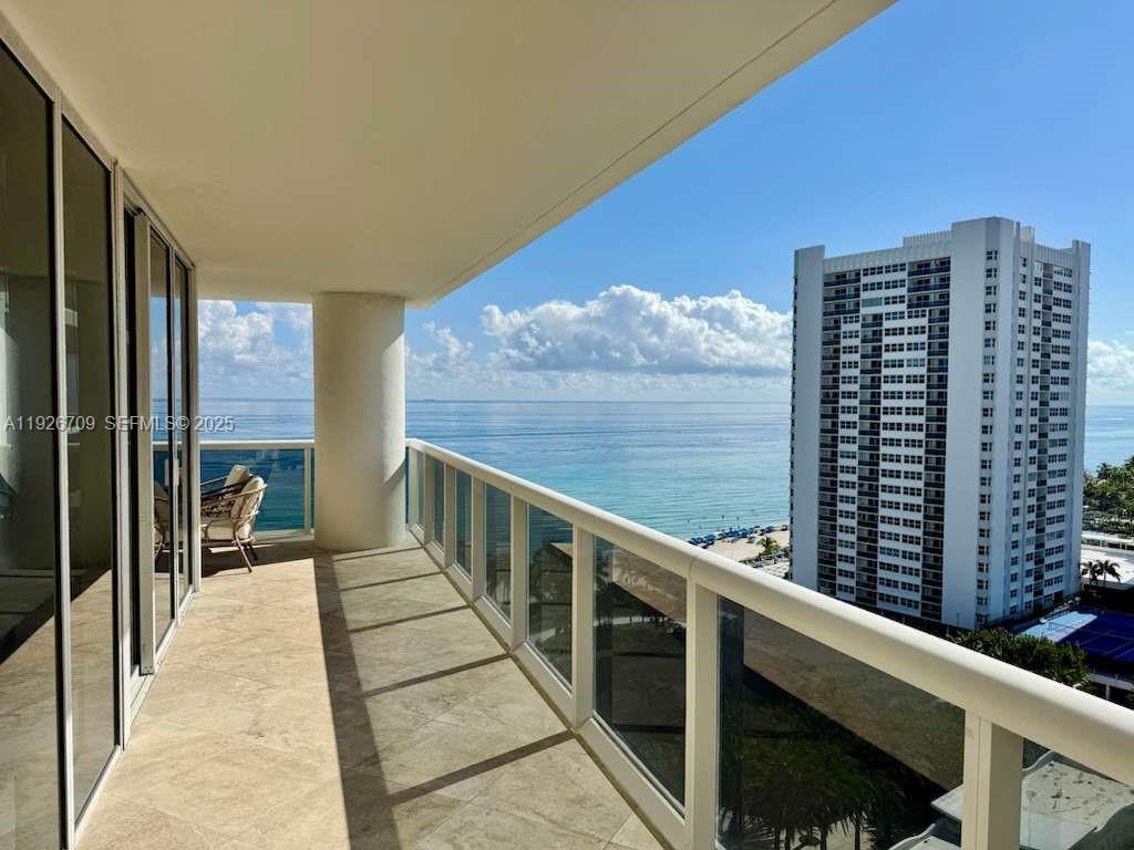 A balcony with tile flooring overlooks the ocean and a neighboring high-rise building — 1850 S Ocean Dr # 1405, Hallandale Beach FL 33009, HALLANDALE BEACH, FL