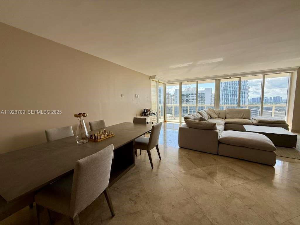 A dining area and living room with tile floors and floor-to-ceiling windows overlooking a city — 1850 S Ocean Dr # 1405, Hallandale Beach FL 33009, HALLANDALE BEACH, FL