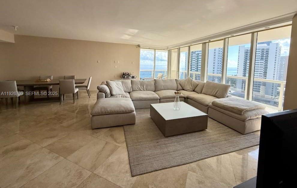 A spacious living and dining area features beige tile floors, a large sectional sofa, and floor-to-ceiling windows — 1850 S Ocean Dr # 1405, Hallandale Beach FL 33009, HALLANDALE BEACH, FL