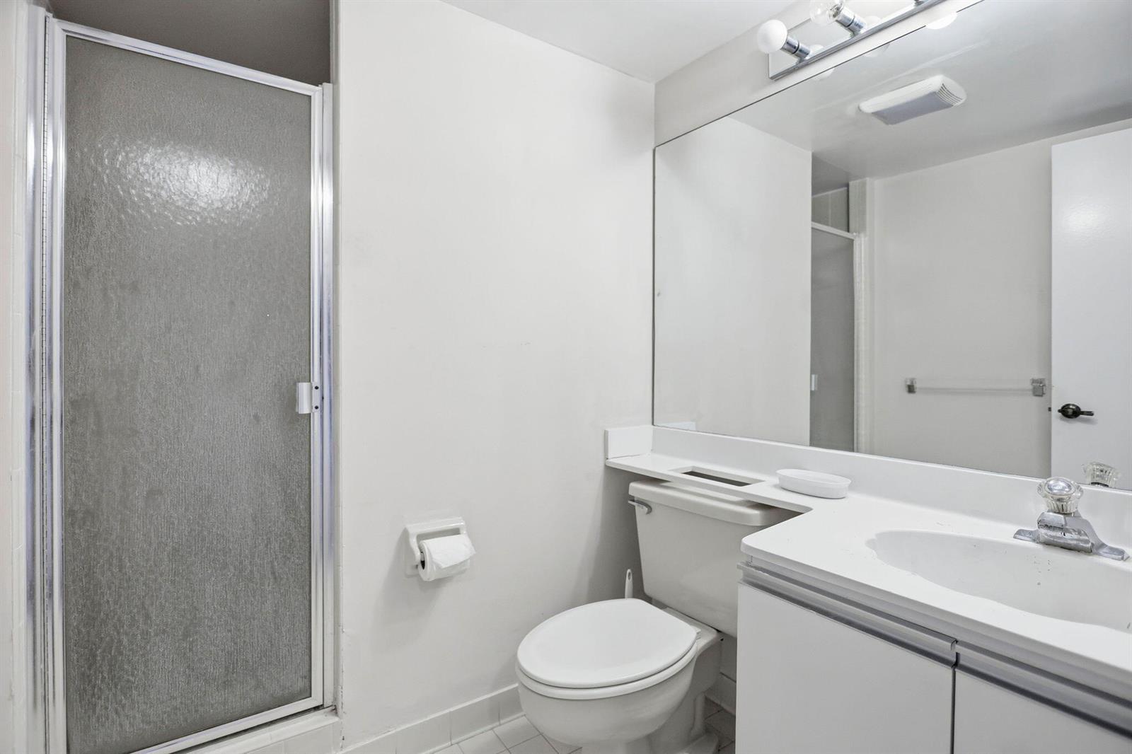 A bathroom features a white vanity, a toilet, a shower stall, and a large mirror — 10110 Cedar Point Boulevard # 206, Boynton Beach FL 33437, BOYNTON BEACH, FL