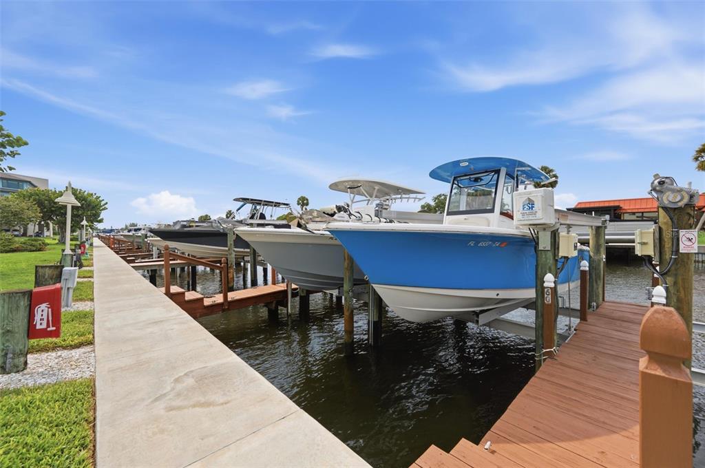 A blue and white motorboat sits on a boat lift at a private residential dock — 9604 CORTEZ ROAD W UNIT 422, BRADENTON, FL