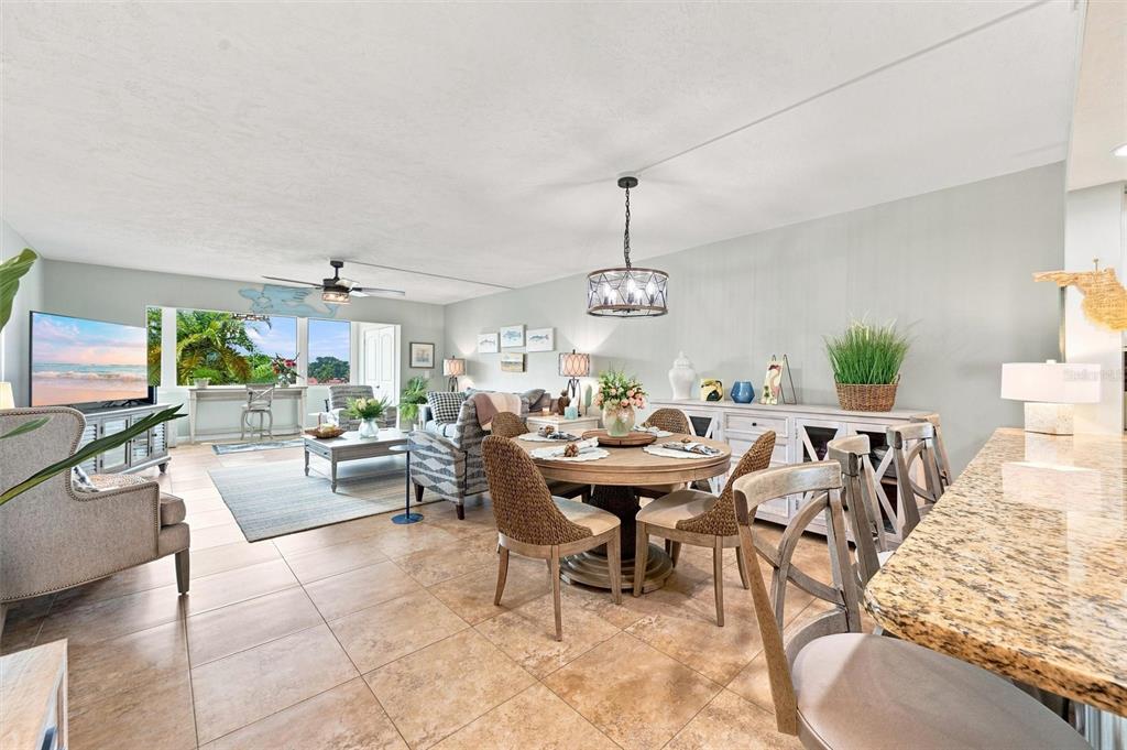 An open-concept living and dining area features tile flooring, neutral walls, and a granite breakfast bar — 9604 CORTEZ ROAD W UNIT 422, BRADENTON, FL